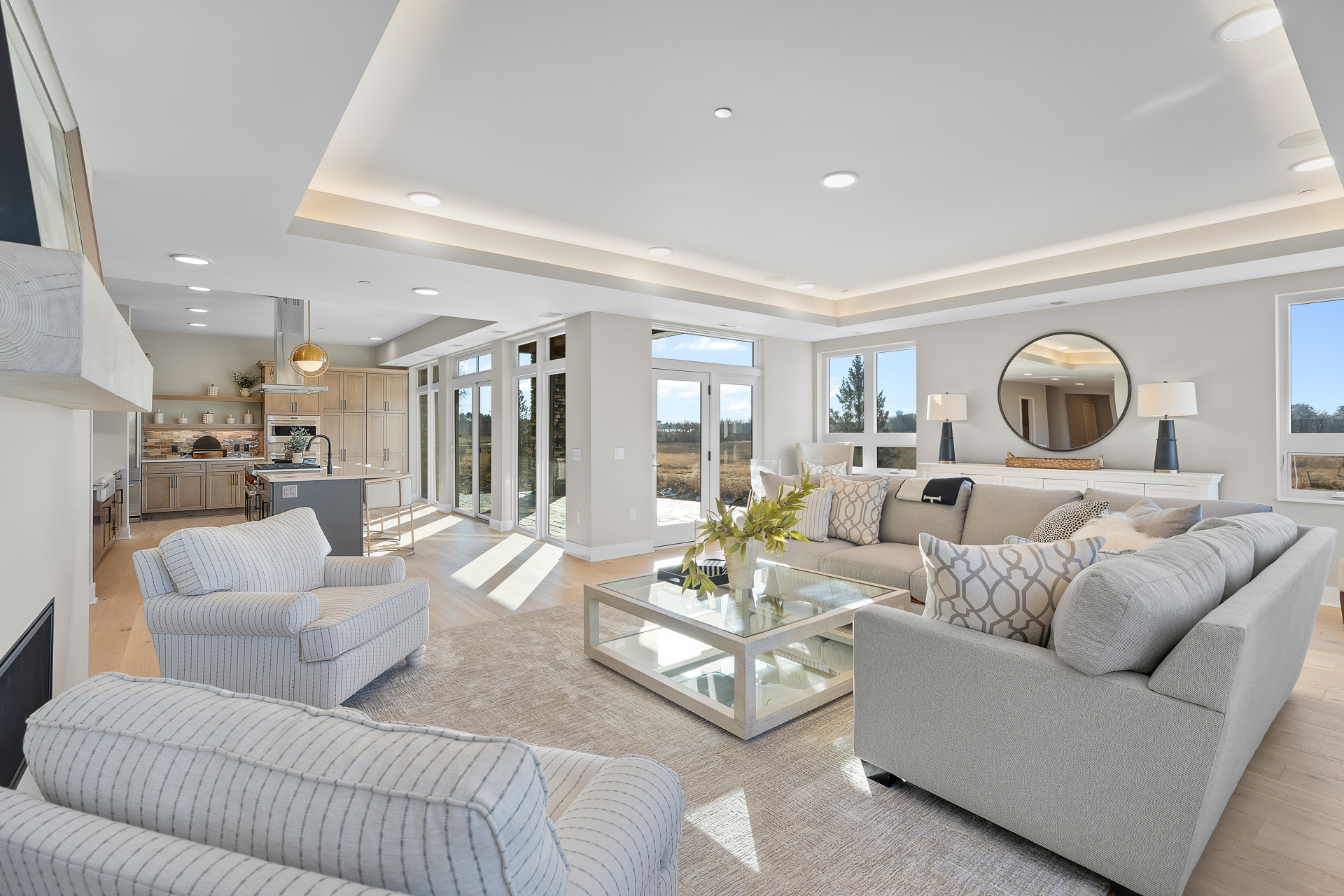 contemporary open concept living room with lots of natural light, large windows, recessed ceiling details and fireplace